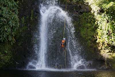 A person abseils  down a waterfall on one of the islands on the Azores.