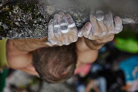 Nahaufnahme der getapten Händen eines Kletterers beim Bouldern.