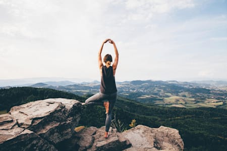 Woman does yoga on top of a mountain.