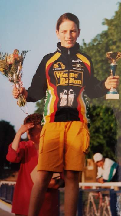 French bike athlete Pauline Ferrand-Prévot holding up a trophy after winning a mountain bike race in the cadet category.