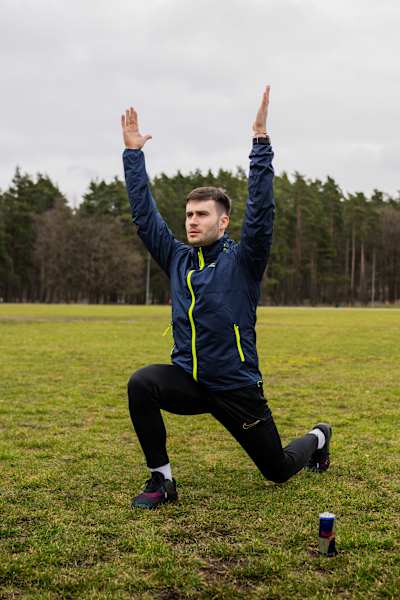 In March 2024, a Lithuanian Wings for Life World Run Ambassador stretches at Vilnius's Vingis Park, ready to embody Red Bull's energetic spirit with a can of Red Bull by his side.