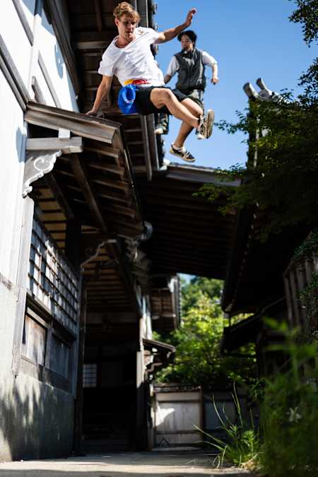 Le freerunner Pasha Petkuns exécute un saut impressionnant entre les toits d’un bâtiment traditionnel japonais lors du tournage de Leap of Faith – Assassin’s Creed à Ise, au Japon.