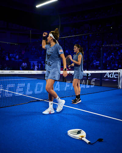 Beatriz González delivers a dynamic performance on the vibrant blue court during the 2025 Red Bull padel tournament, showcasing her power and determination under the stadium lights.