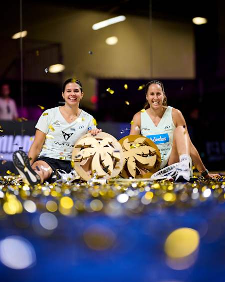 Delfina Brea y Gemma Triay celebran su triunfo en el torneo Motorola Razr Miami Premier Padel P1 en Miami, EE.UU., 2025, sosteniendo sus trofeos de ganadoras en medio de un ambiente festivo.
