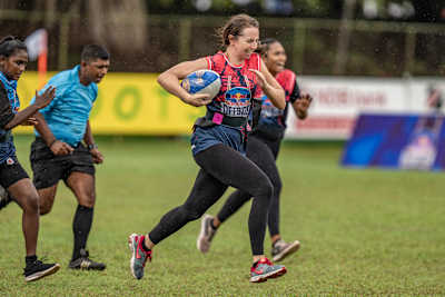 Une joueuse de rugby court avec le ballon lors d’un match.