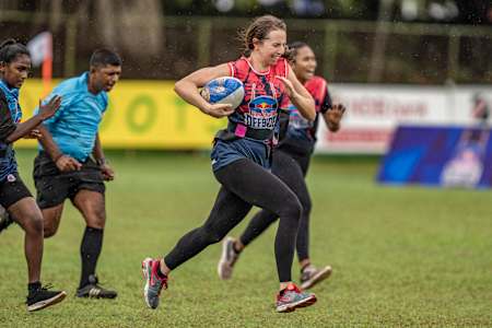 Une joueuse de rugby court avec le ballon lors d’un match.