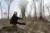 Person doing a pistol or one-legged squat in woods.