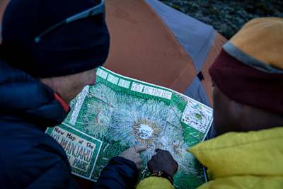Two people point to a section of a map while navigating.