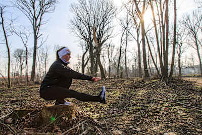 Person doing a pistol or one-legged squat in woods.