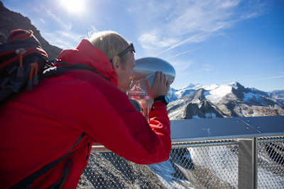 Person looks at mountains through a viewfinder in Austria.