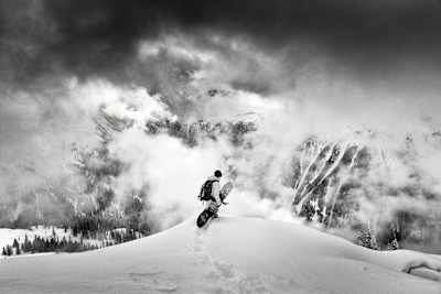 Snowboarder overlooking a snowy mountain panorama.