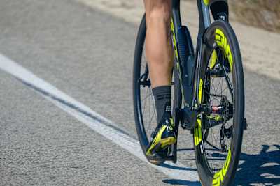 Close up of a triathlete riding a triathlon bike on a road whilst wearing compression socks.