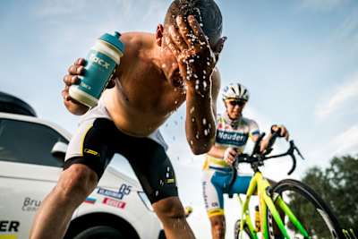 長いステージを終えて頭から水をかぶるサイクリスト