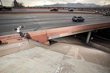 CJ Collins skating a freeway ledge to bank by Dave Swift.
