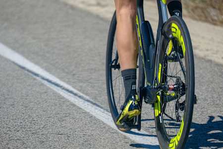 Close up of a triathlete riding a triathlon bike on a road whilst wearing compression socks.