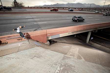 CJ Collins skating a freeway ledge to bank by Dave Swift.