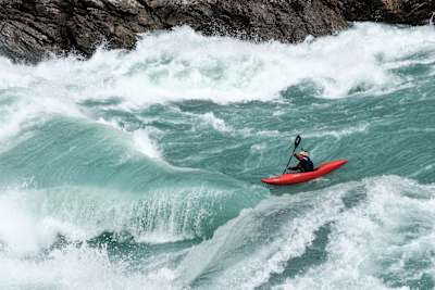 Nouria Newman paddles through high volume river.