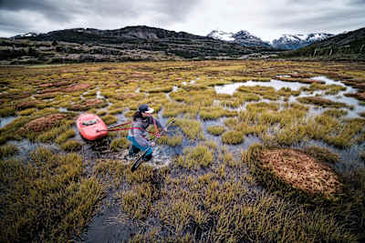 Nouria Newman tows her kayak through swampy waters in Patagonia.