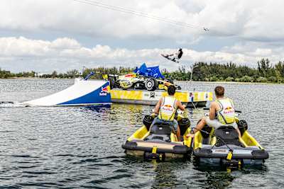 F1 vozači Liam Lawson i Arvid Lindblad gledaju kako wakeboarder Guenther Oka otkriva VCARB-ovu livreju za Miami GP 29. aprila 2026.