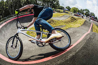 BMX rider goes around berm on a pump track.