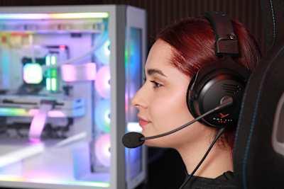 Bild zeigt eine junge Frau mit dem beyerdynamic MMX 330 Pro Gaming-Headset mit einem Gaming-PC im Hintergrund.
