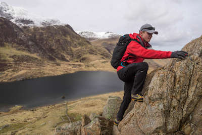 Man scrambles up rock face in Wales.