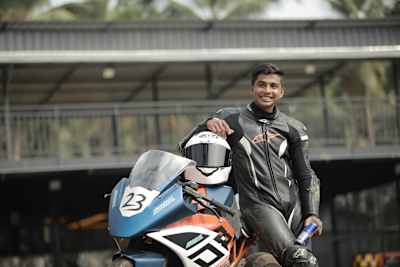 Bike racer Anfal Akdhar stands with his bike while drinking Red Bull.