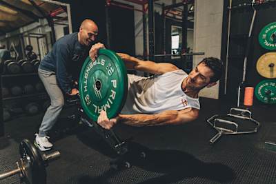 Gee Atherton training in the gym with a helper