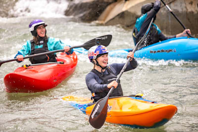 Evy Leibfarth smiling in kayak on the water, joined by two other kayakers