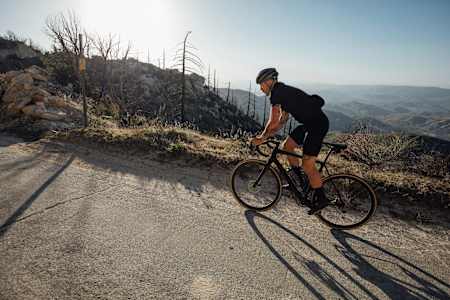 Cyclist rides a Cannondale Synapse bike up a hill.