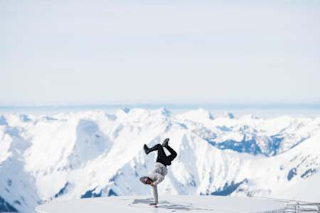 El b-boy Junior actúan en la cima de una montaña de los Alpes suizos.