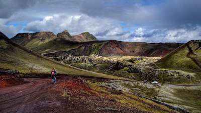 Pessoa caminha sobre a suntuosa paisagem do parque natural de Landmannalaugar na Islândia