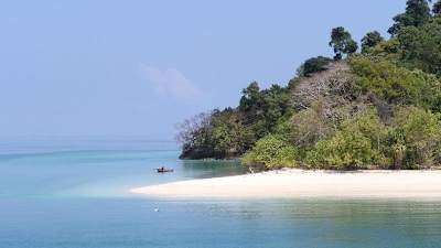 Ilha com praia branca vazia e mar azul.