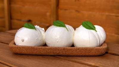 Bolas de mozzarella com uma folha de manjericão por cima.