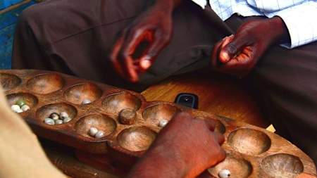 Two people play the game of Awari.