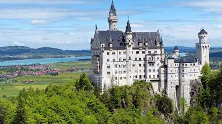 Neuschwanstein Castle overlooking forest and mountains.