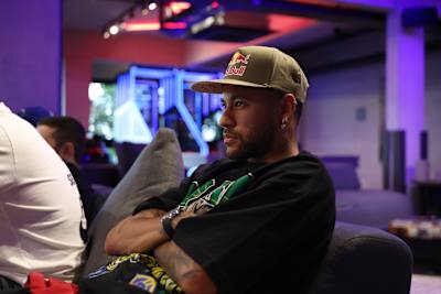 Le joueur de football Neymar Jr est assis sur un canapé pendant qu'il regarde la télévision avec ses amis.