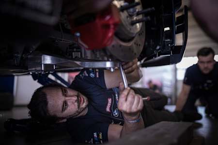 Ein Mechaniker der Red Bull Driftbrothers liegt unter den Drift-Auto schraubt am Fahrwerk des neuen BMW G82 M4 Competition Cars herum.