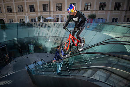 Fabio Wibmer balances a bike on an escalator rail.
