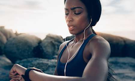 Biegaczka spogląda na zegarek biegowy - sprawdza tempo.