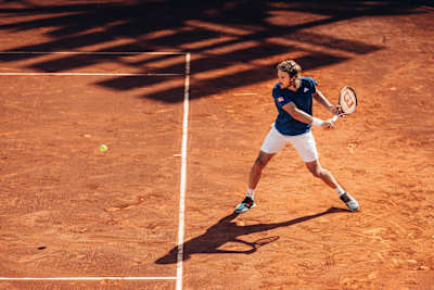 An image of Greek tennis player Stefanos Tsitsipas playing on a clay court.