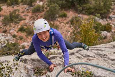 Climber smiles up at camera while on rock face.