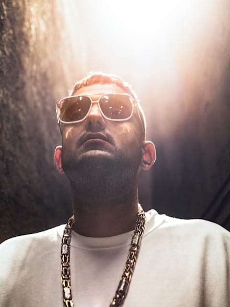 Haftbefehl mit Kette, Brille und der Sonne im Rücken