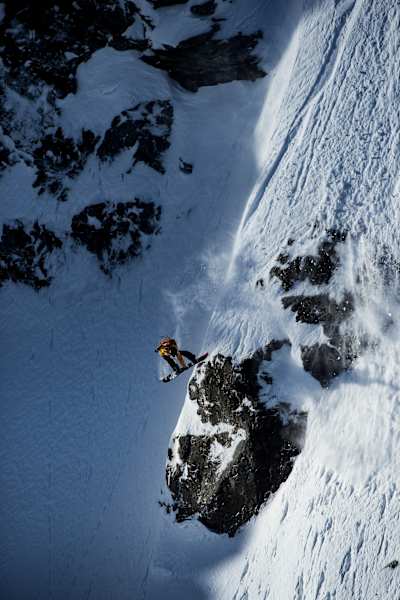 An image of a snowboarder in action descending a steep mountain.