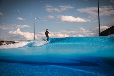 Surferin macht auf einer Welle des o2 SURFTOWN MUC einen Noseride auf einem Lonboard.