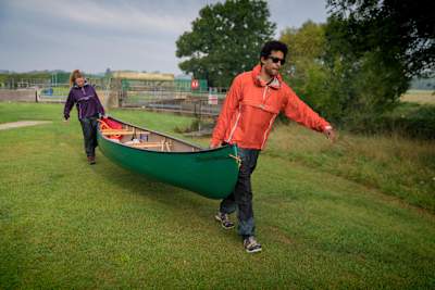 People carry a canoe wearing Páramo Adventure Trousers.