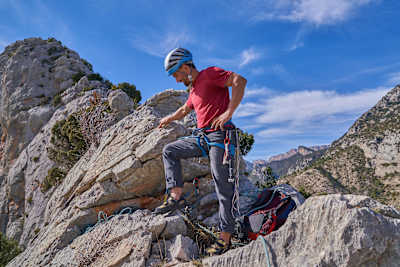 Climber at top of ridge looks down granite rock face in Catalunya, Spain.