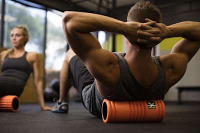 A man relaxes with a foam roller on his back.