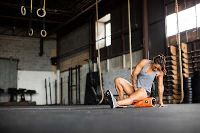 A woman uses the foam roller on her leg muscles.