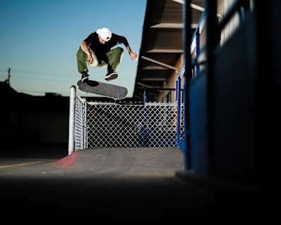 Skateboarder TJ Rogers floats a Backside 180 Nollie Kickflip over a fence.